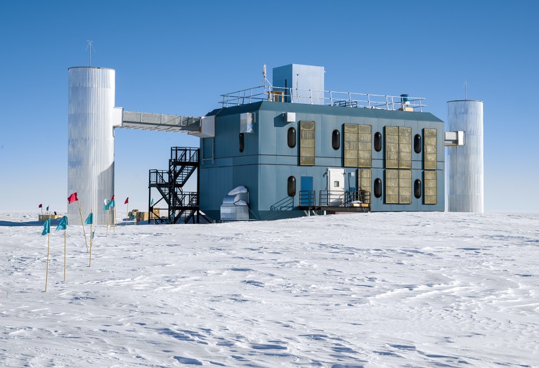 The IceCube Neutrino Observatory at the South Pole on a bright sunny day on flatland covered in snow.