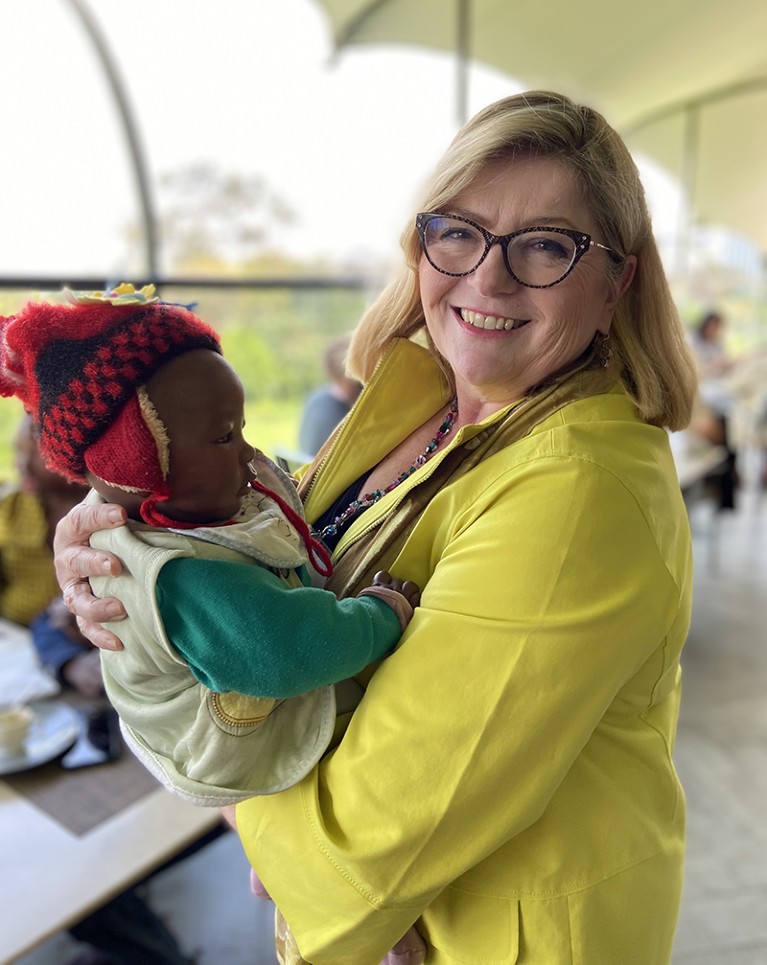 Sharon Hillier smiles at the camera as she holds a baby.