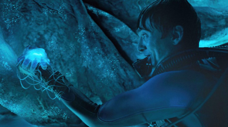 Movie still from Whalefall showing a scuba diver inside a large whale, admiring a glowing jellyfish.