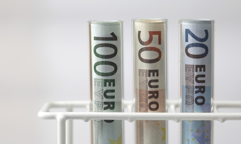 Euro banknotes rolled up in test tubes