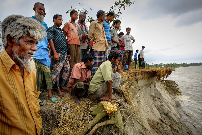 A group of villagers stands beside the Jamuna River in Bangladesh