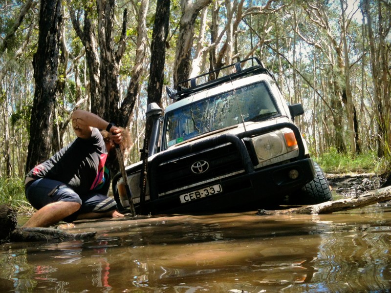 Man trying to dig a 4x4 out of a puddle