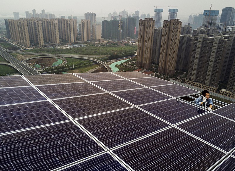 A worker from the Wuhan Guangsheng Photovoltaic Company talks on his phone as he works on a solar panel project in China, 2017.