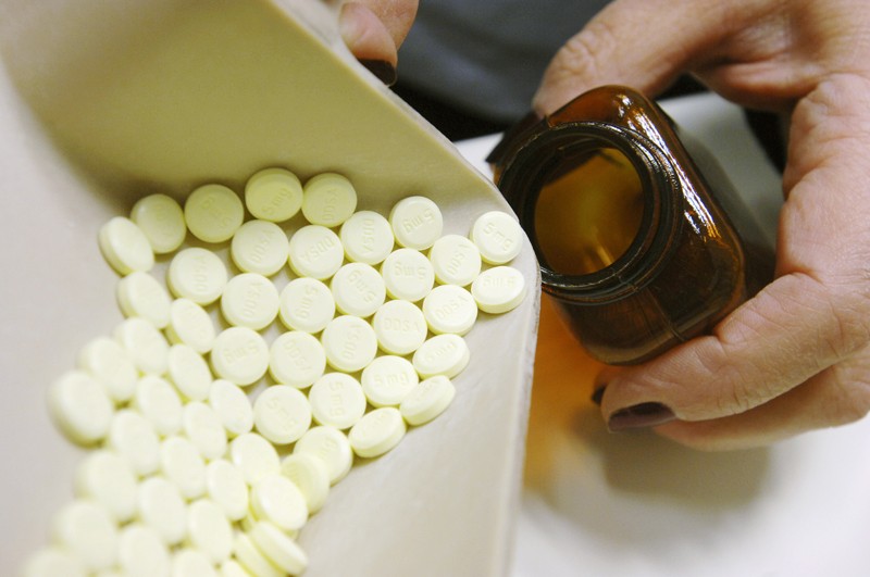 Pharmacist dispensing diazepam tablets into pill bottle