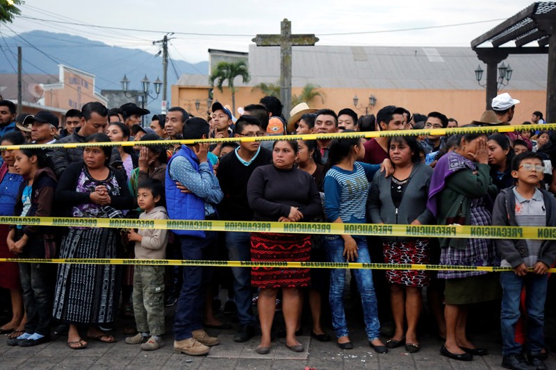Residents stand behind a cordon after the Fuego volcano erruption