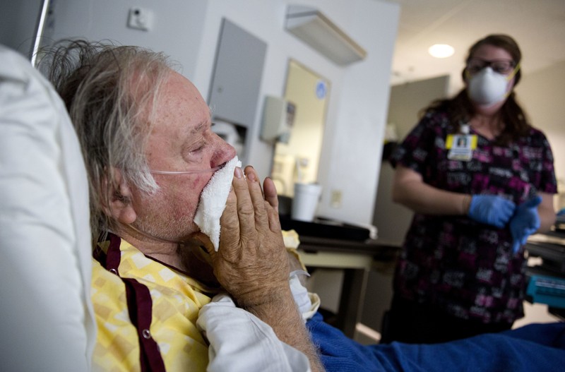 A man with the flu is tended to by a nurse