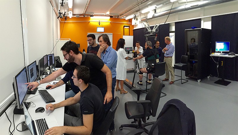 View of the experimental platform. Researchers look at data on screens to the left, a patient is in the rigging at right