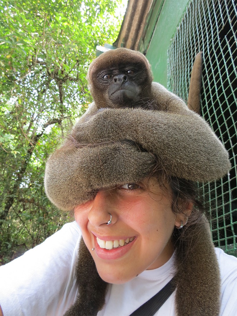 A woolly monkey sits on the head of Bárbara Cartagena Matos in the Amazon