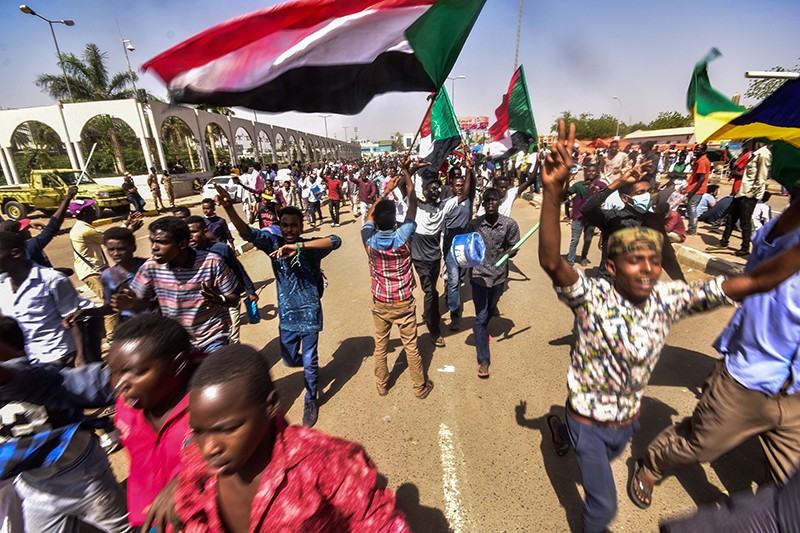 Sudanese demonstrators march with national flags in Khartoum