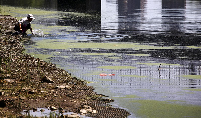 A woman washes clothes in a polluted canal in central Beijing, China.