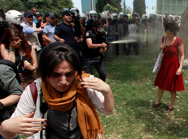 A Turkish riot policeman uses tear gas as people protest against the destruction of trees in a park