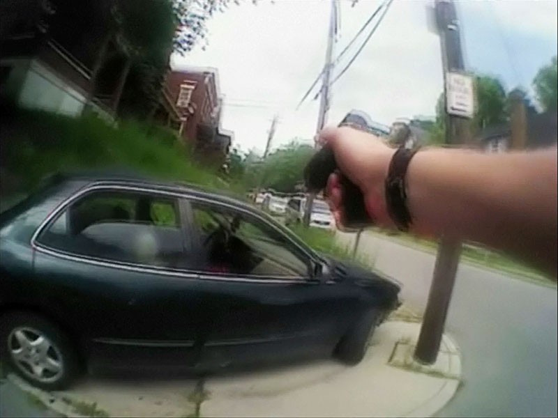 A video still from a police officer's body camera shows his handgun drawn after a driver was shot during a traffic stop in Ohio