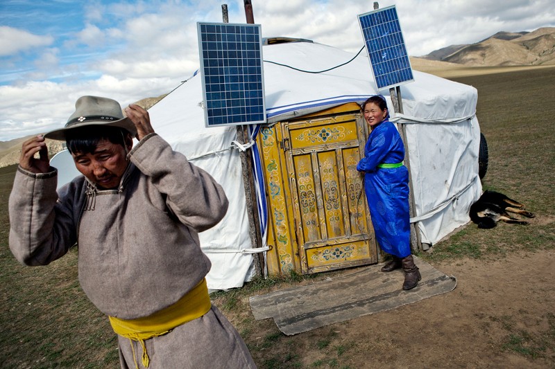 A couple stand outside their yurt with solar panels near Ulaanbaatar, Mongolia.