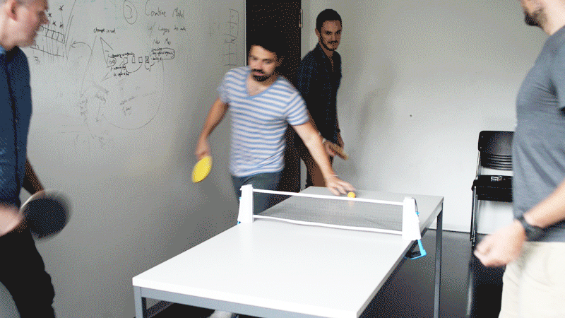 Members of the Crowther Lab play a game of their own invention around a small ping-pong table in Thomas Crowther’s office