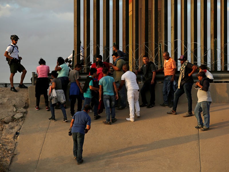 A US Customs and Border Protection agent stands next to migrants who crossed illegally from Mexico into El Paso, Texas.