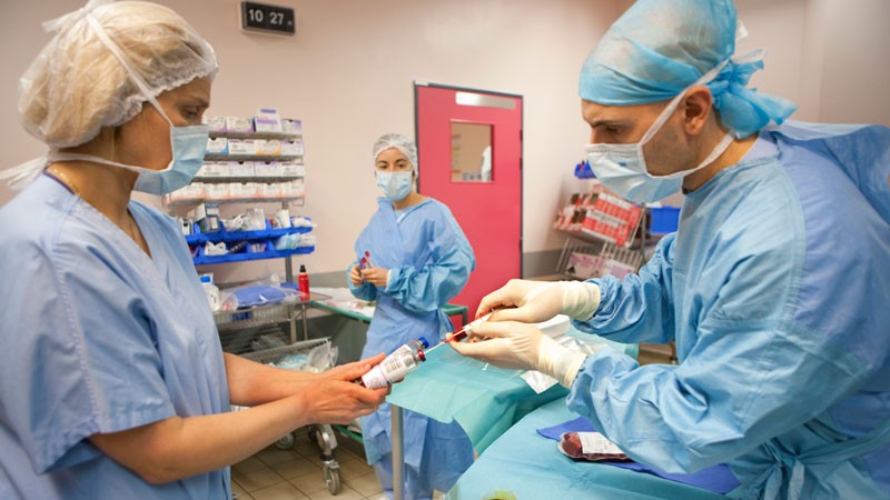 Medical personnel in surgical scrubs preparing for a procedure.