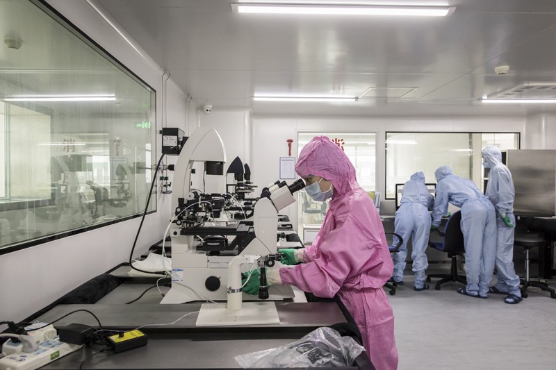 Technician using a microscope inside a laboratory in China.