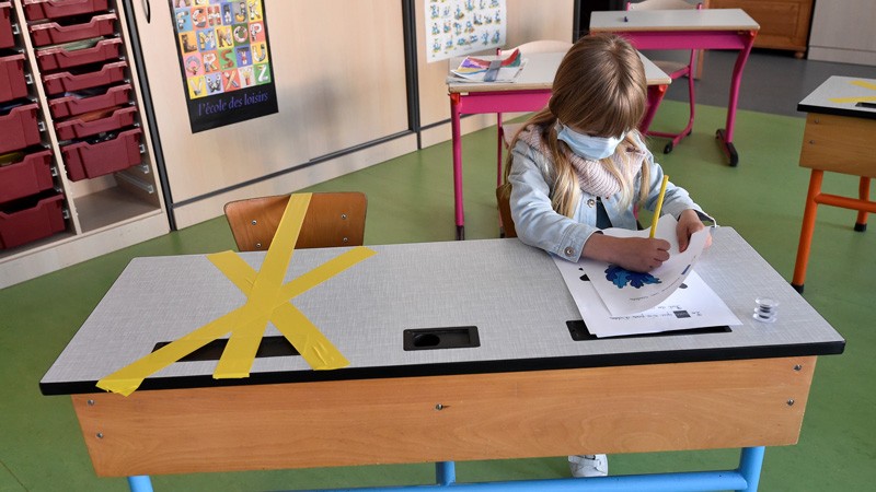 A pupil of the Sainte-Croix elementary school works as half of her writing desk is marked to ensure safe distance, France.