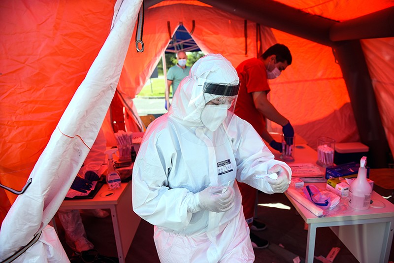 A health worker wears protective gear while leaving a tent with a saliva sample for Covid-19
