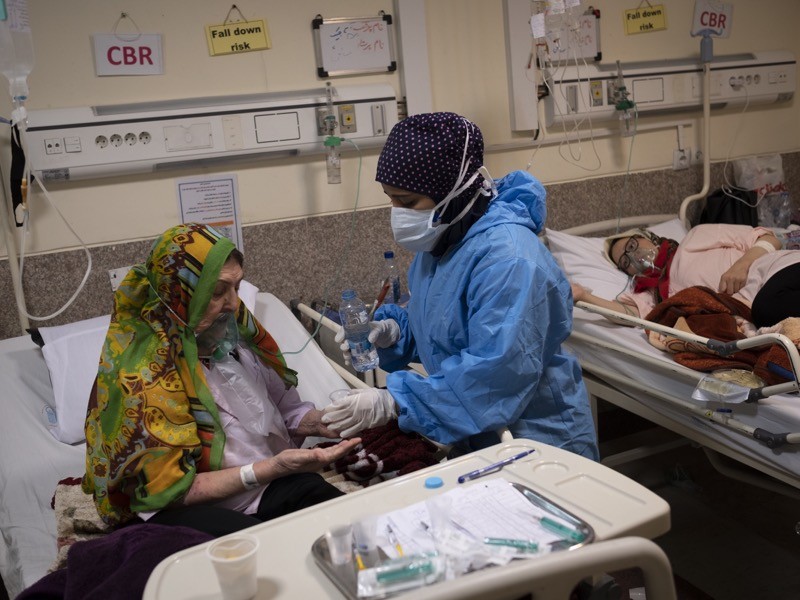 Iranian medical personnel wearing a protective suit takes care of an elderly woman infected with covid.