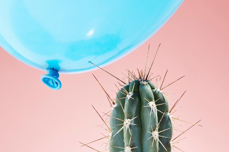 The needle on a cactus pressing into the surface of a balloon.