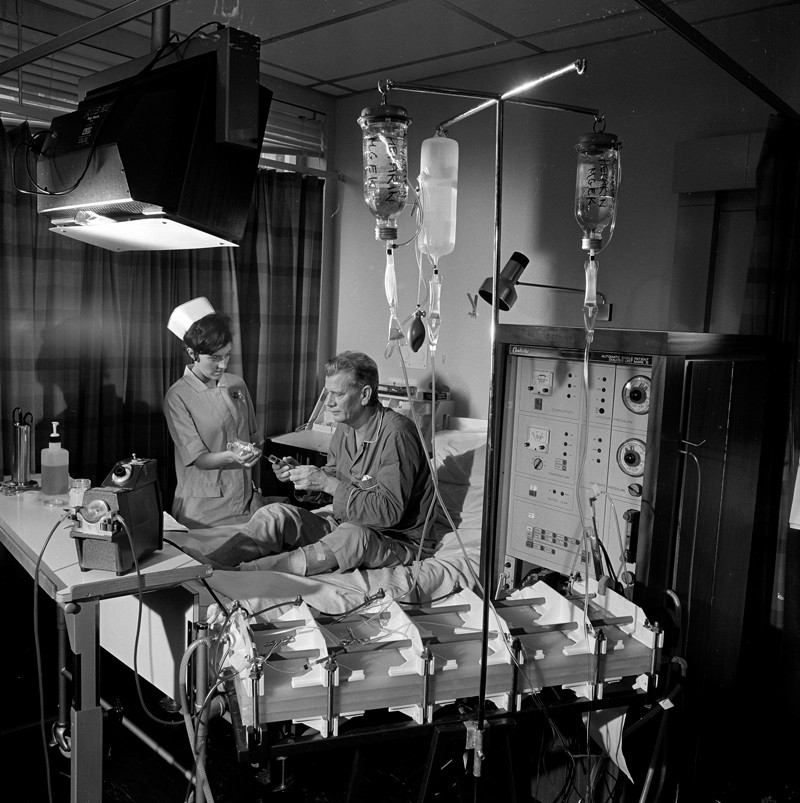 Een verpleegster verzorgt een patiënt met een groot dialyseapparaat in een ziekenhuis in 1968