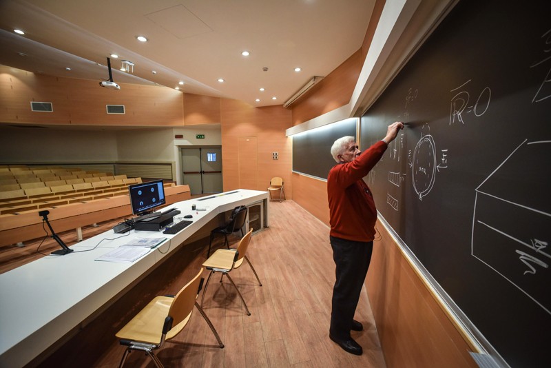 A university professor holds an online lecture from an empty lecture theatre.