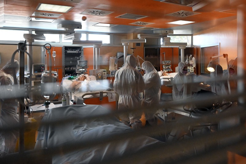 Medical workers in protective gear tend to patients in an intensive care unit.