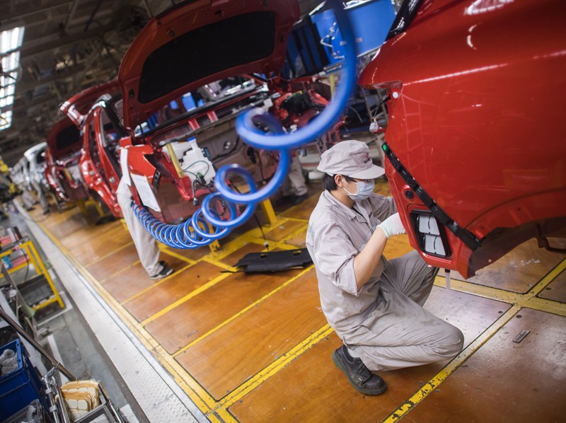 A worker wearing a face mask works on a car production line in a factory in Wuhan, China