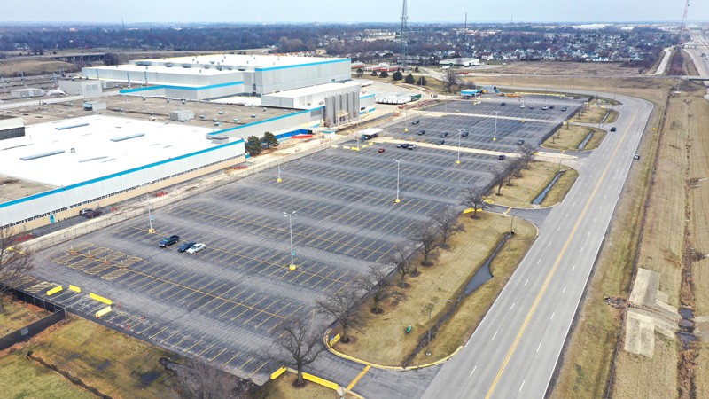 Aerial view of a large car park in an industrial area, with only a few cars present.