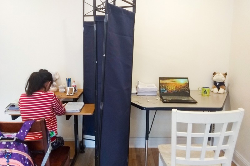 Workstations separated by a screen. A girl sits at one desk.