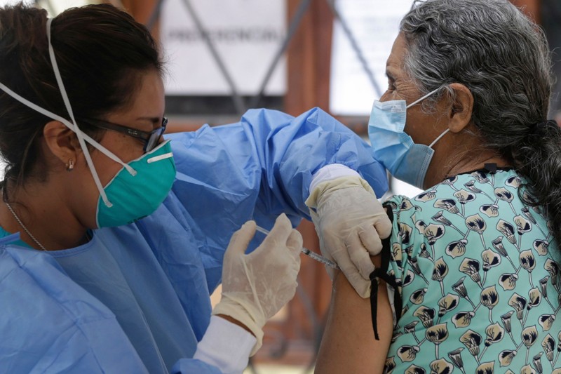 A nurse injects an elderly woman with an influenza vaccine in Lima, Peru