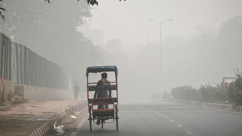 A rickshaw puller rides along a road under heavy smog conditions in New Delhi.