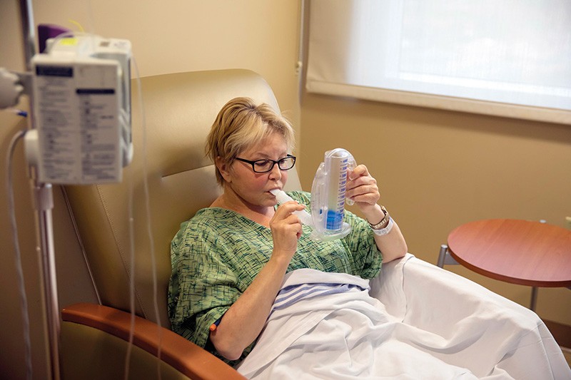 Un paziente su una sedia ospedaliera soffia in uno spirometro