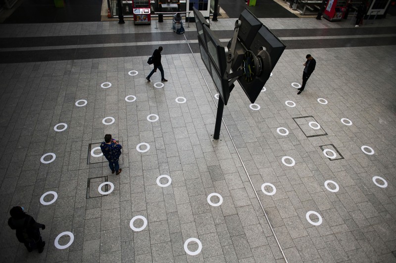 Commuters walk over a pattern of circular distancing markers on the concourse at the Gard du Nord, Paris.
