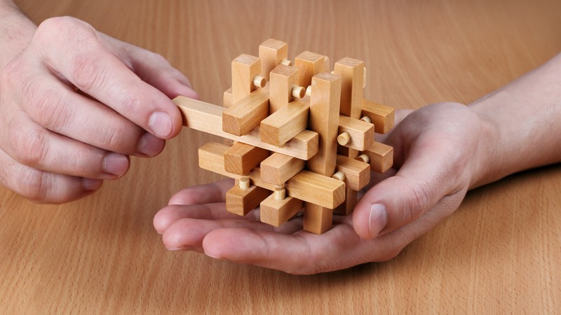 Completed wooden puzzle in hands on the background of the table.