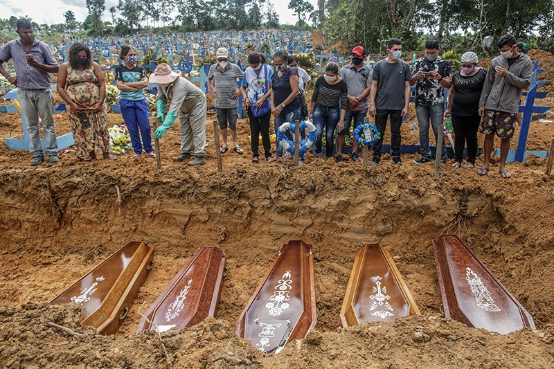People in protective masks at the graveside during a mass burial of COVID-19 victims in Manaus, Brazil.