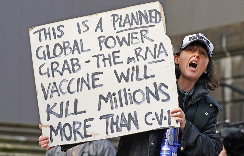 A protester holds a banner claiming that the COVID-19 vaccine will kill millions