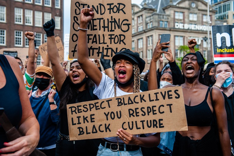 A Black woman holds a placard during a protest against anti-Black violence.