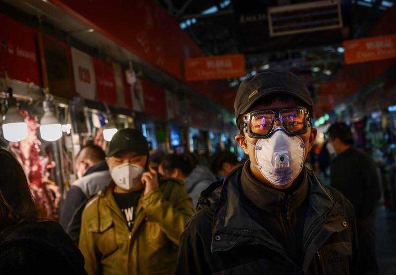 A Chinese man wears a protective mask and goggles as he shops at a local market