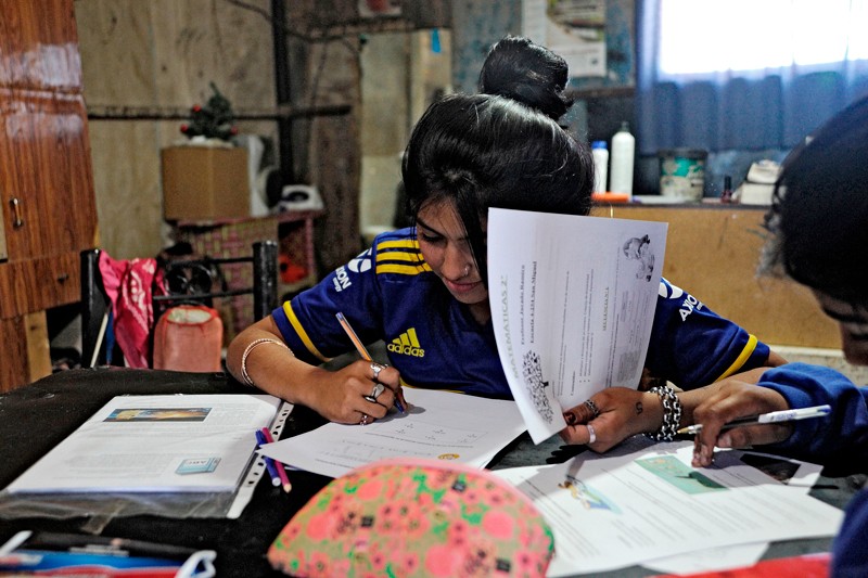 A teenage girls sitting at a table in her home writing in school worksheets