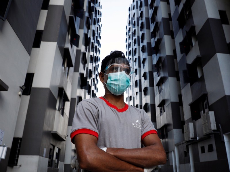 A migrant worker listens as officials give a tour of a dormitory, Singapore.