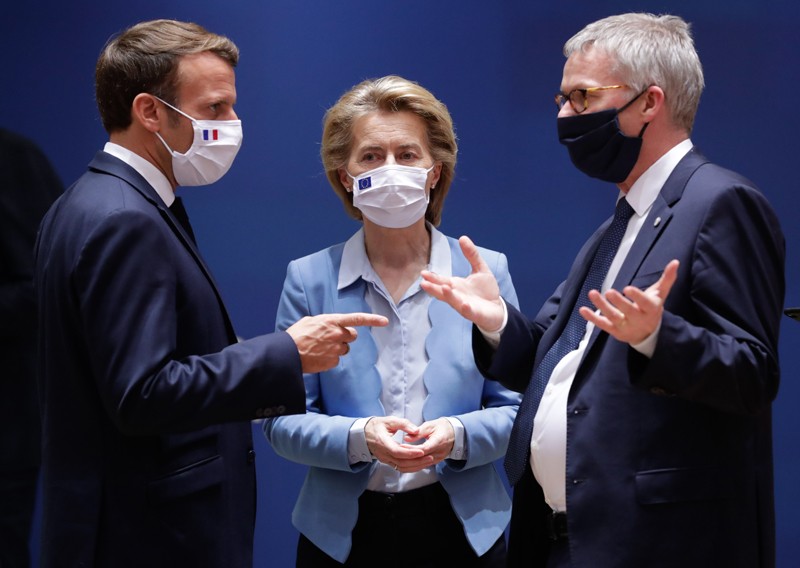 Three people wearing facing masks, standing close together and talking.