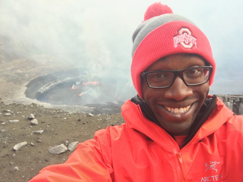 A man in a woolly hat and anorak on the edge of a volcano.