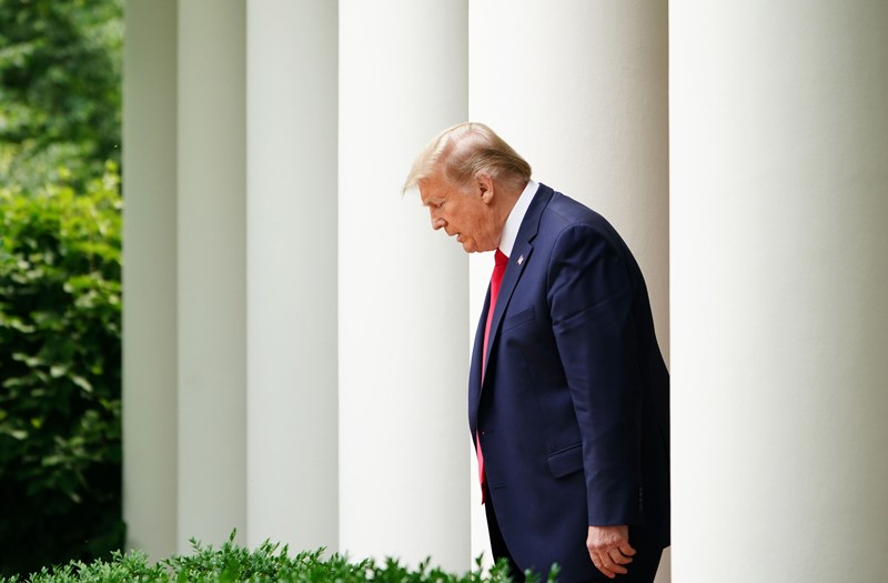 US President Donald Trump walks through a row of white pillars into the Rose Garden at the White House