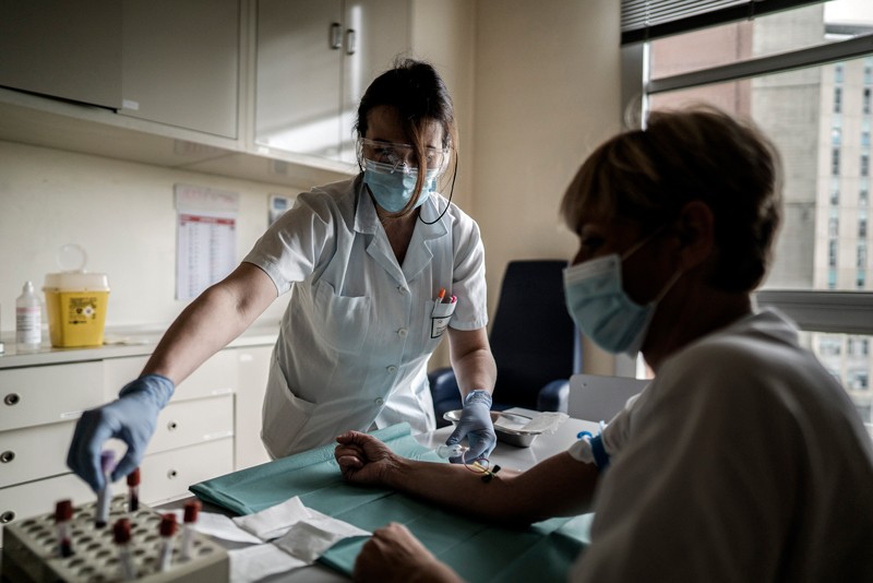 A health care worker takes blood samples from a patient for a coronavirus antibody test