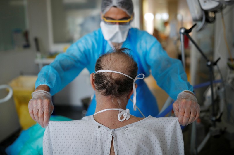 A physiotherapist wearing protective clothing assists a patient suffering from Covid-19 in a hospital in France