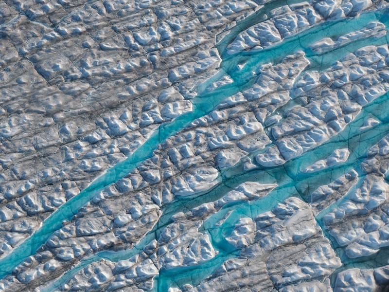 Figure 1: In this view from an airplane rivers of meltwater carve into the Greenland ice sheet, near Ilulissat, Greenland.