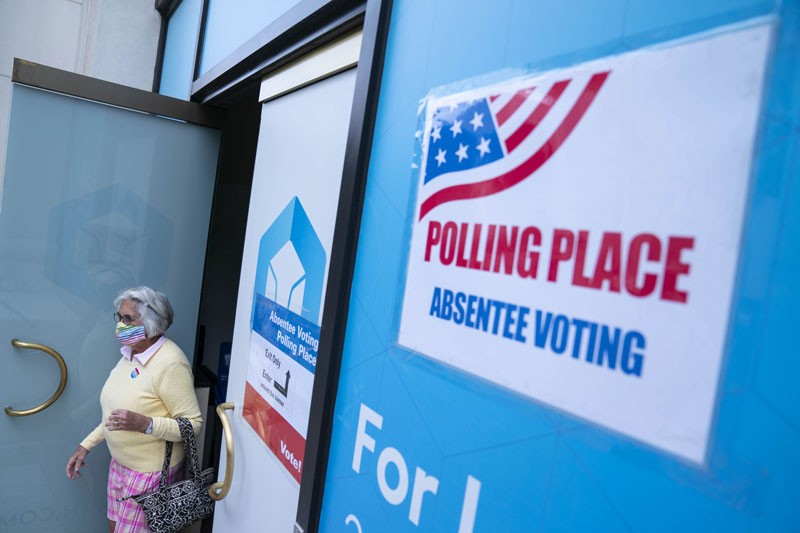 A voter wearing a protective mask exits from an early voting polling location