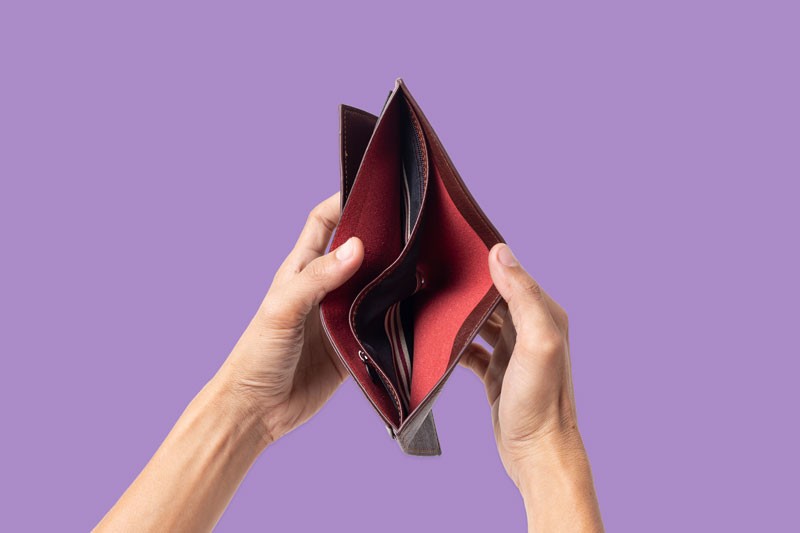 Hands holding an empty wallet isolated on a purple background